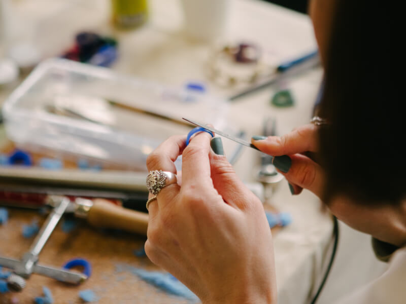 A close up of a person filing the wax mold to make a silver ring